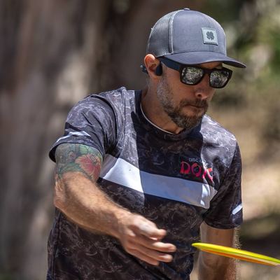 Ryan Milani releasing a disc mid-throw in a Disc Golf Dojo jersey